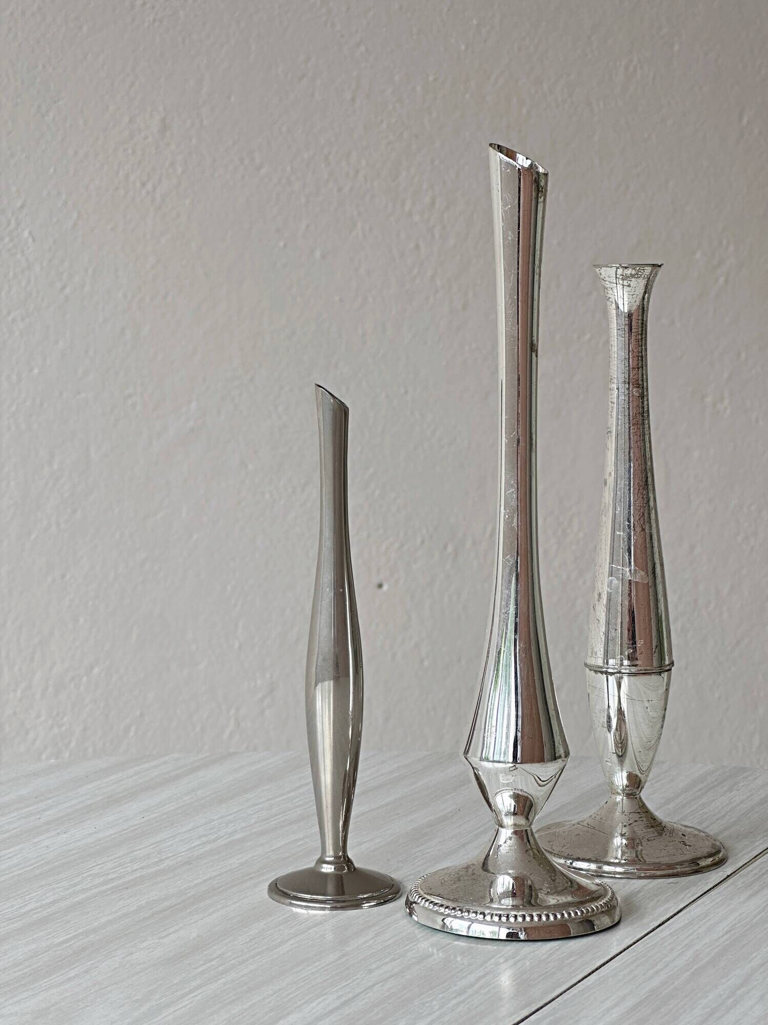 Set of three lightweight silver-coloured metal vases.