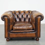 A well-maintained cowhide leather English Chesterfield armchair