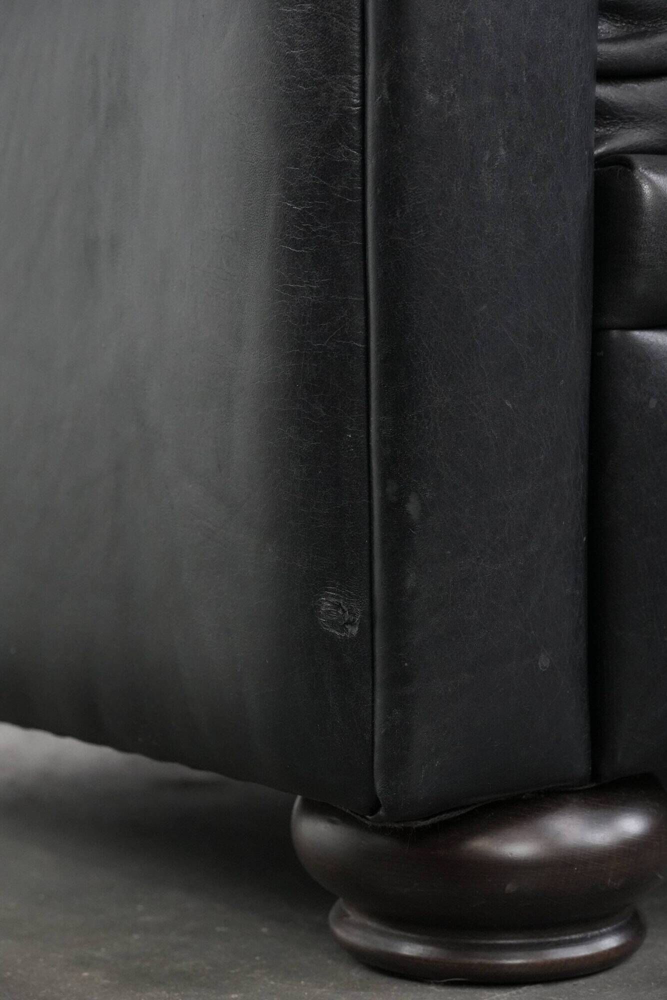 Set of a black cowhide leather Chesterfield armchair and matching ottoman