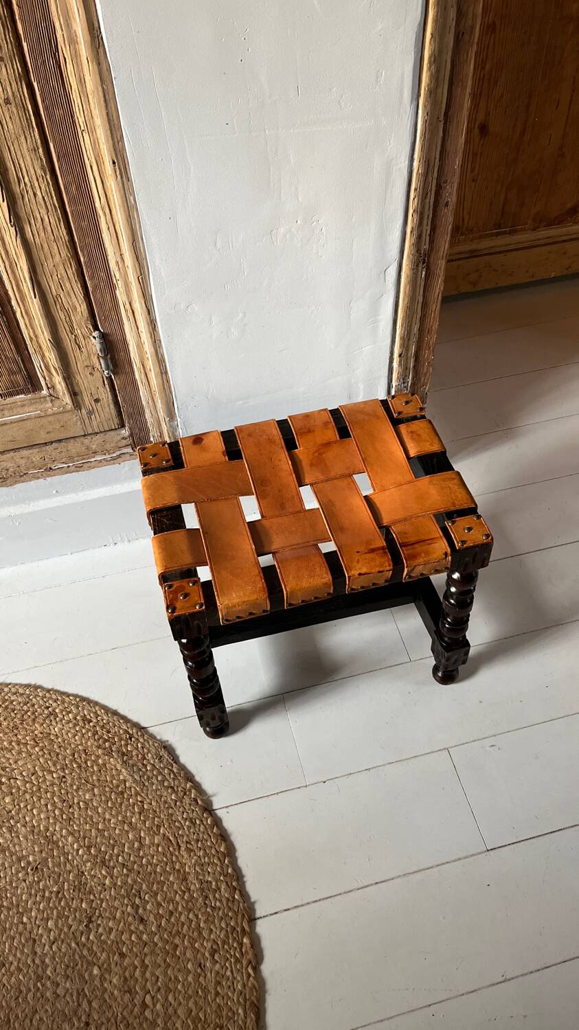 Antique turned wooden stool with woven leather.