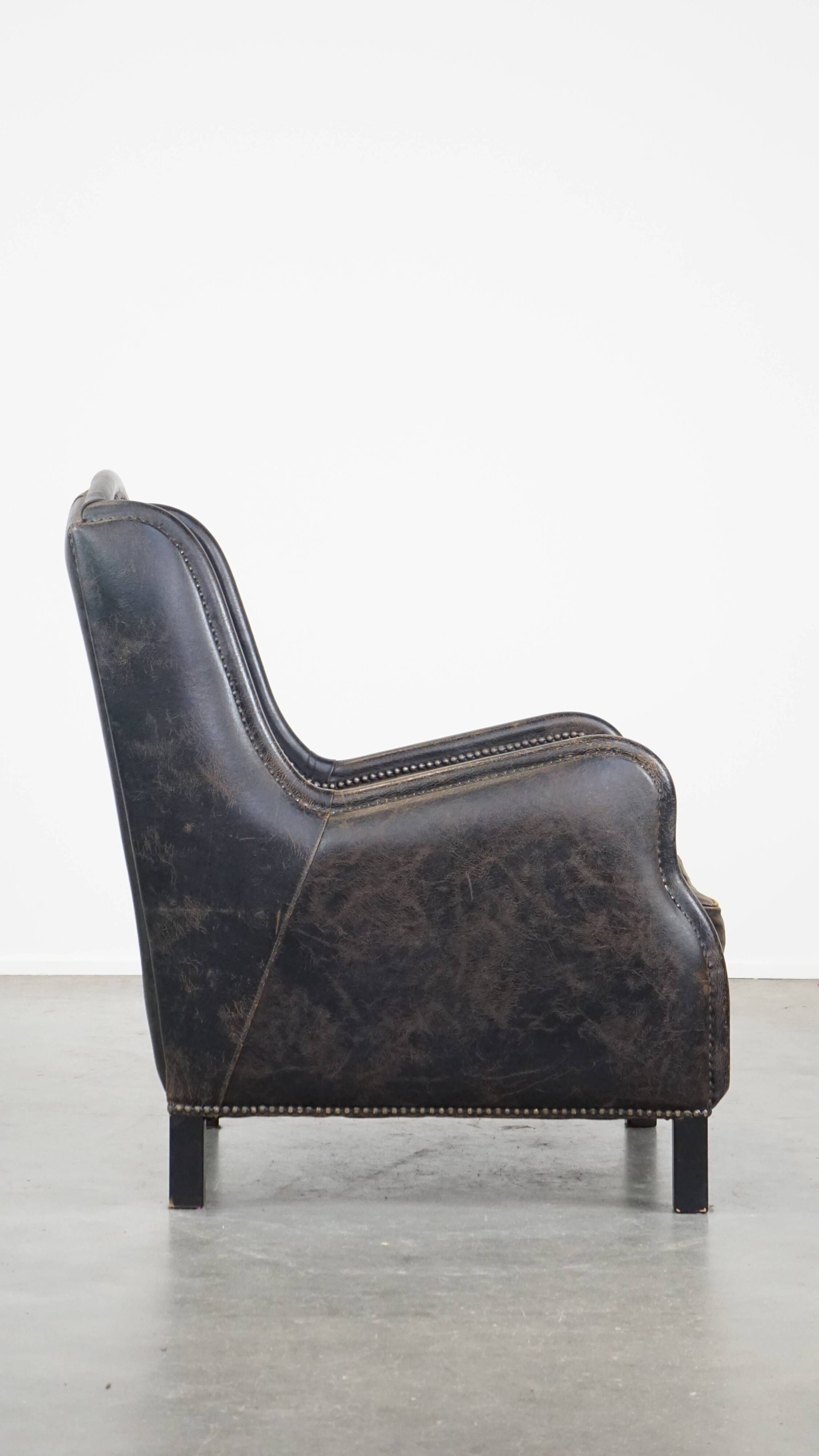 Black cow leather armchair finished with decorative nails, industrial style