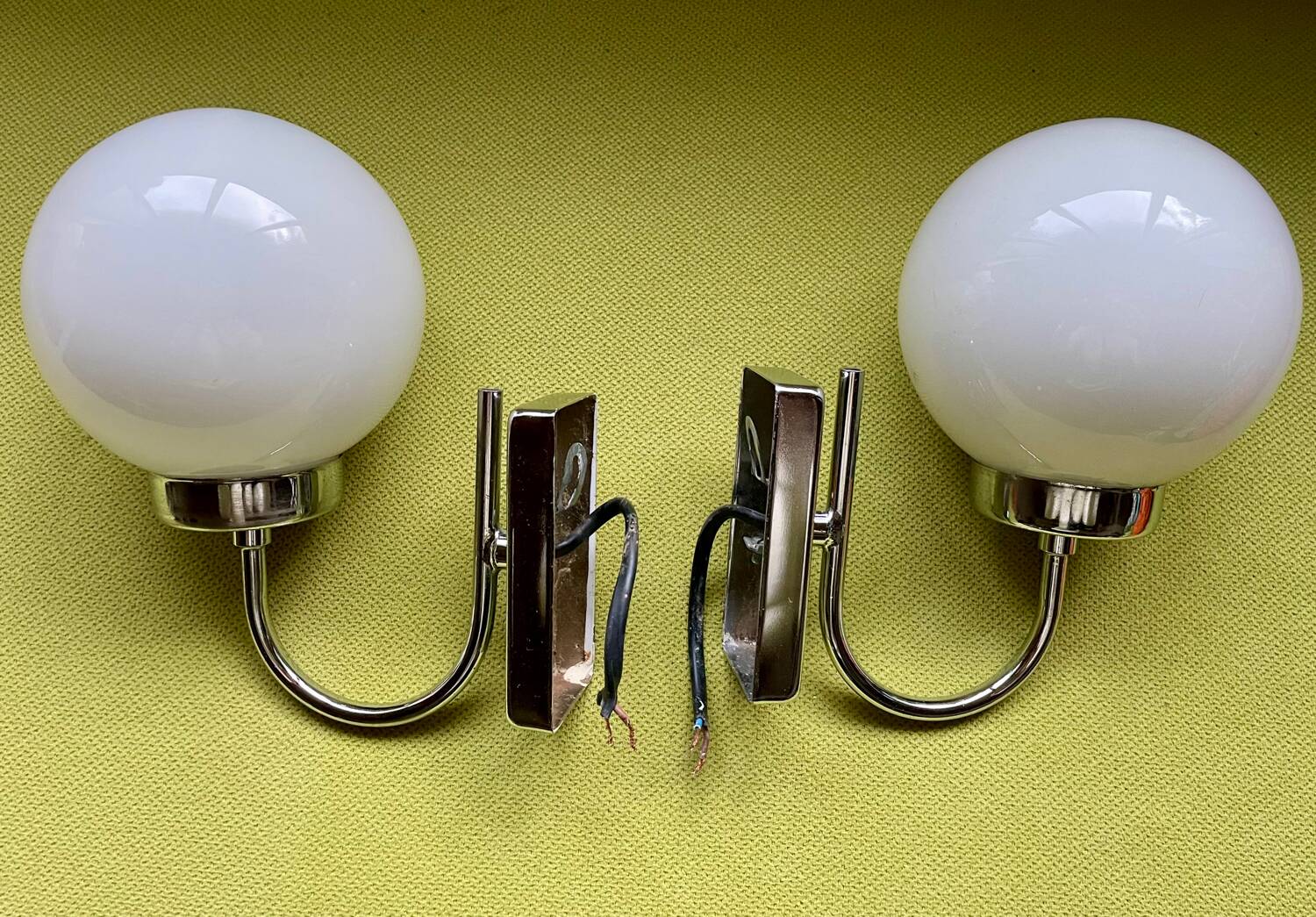Pair of chrome metal wall lights with white glass globe.