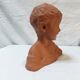 Terracotta bust of a smiling little boy.