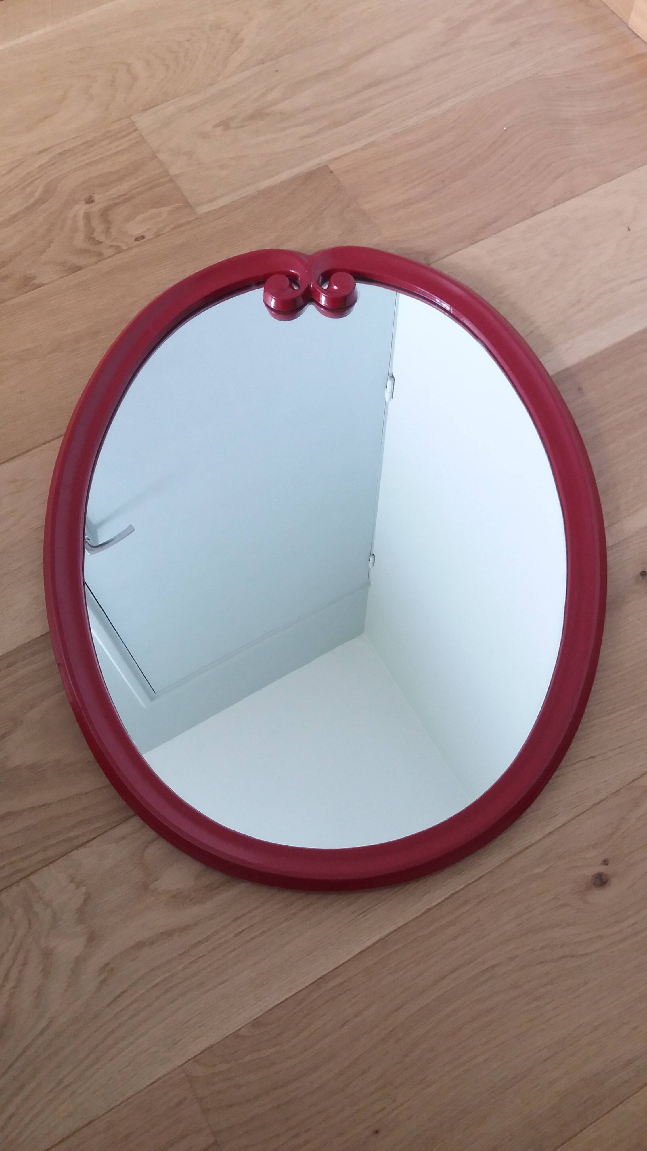 Oval mirror, red enamelled metal in Art Deco style, 49 x 39 cm.