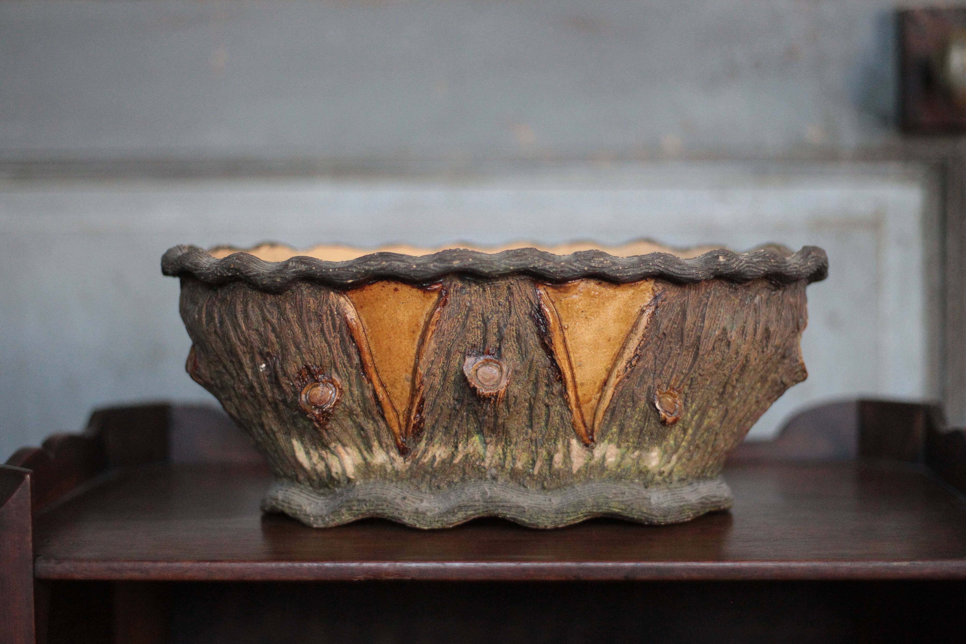 Terracotta planter in a brutalist style resembling a tree trunk, pot cover, countryside.