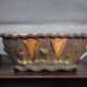 Terracotta planter in a brutalist style resembling a tree trunk, pot cover, countryside.