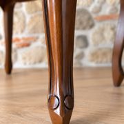 Two-seater bench in carved wood, with curved armrests.