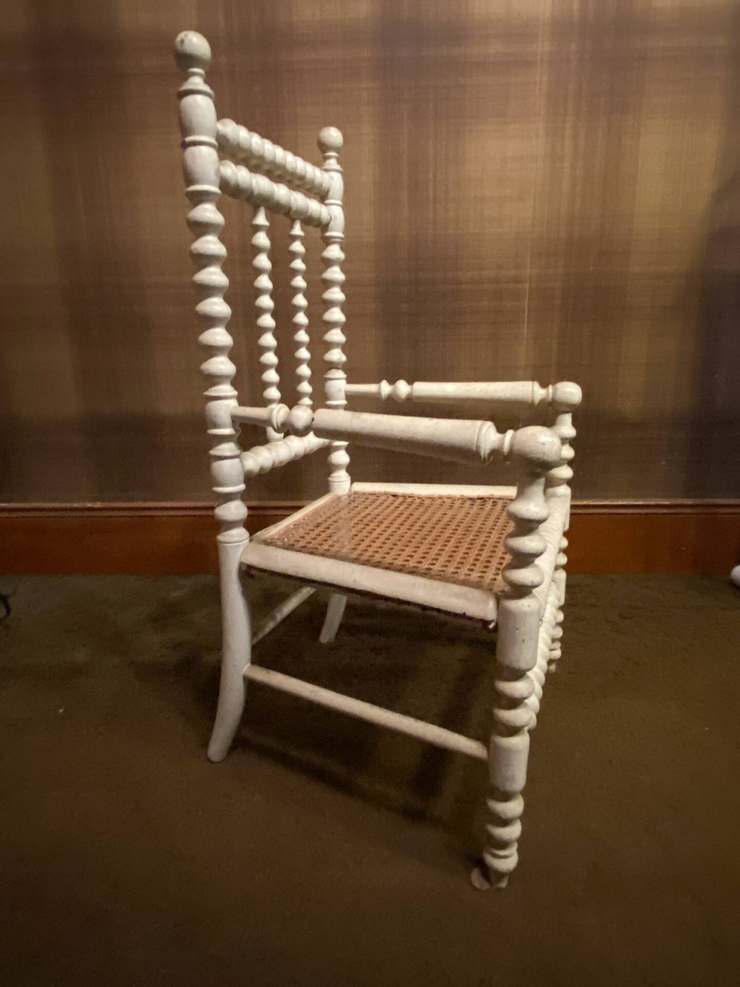 Antique wooden child's chair with turned legs and caning, white patina.