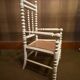 Antique wooden child's chair with turned legs and caning, white patina.