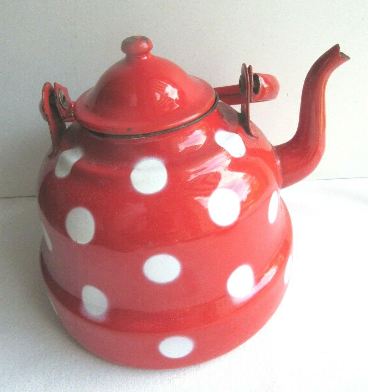 Old vintage kettle in red enamelled sheet metal, with white polka dots