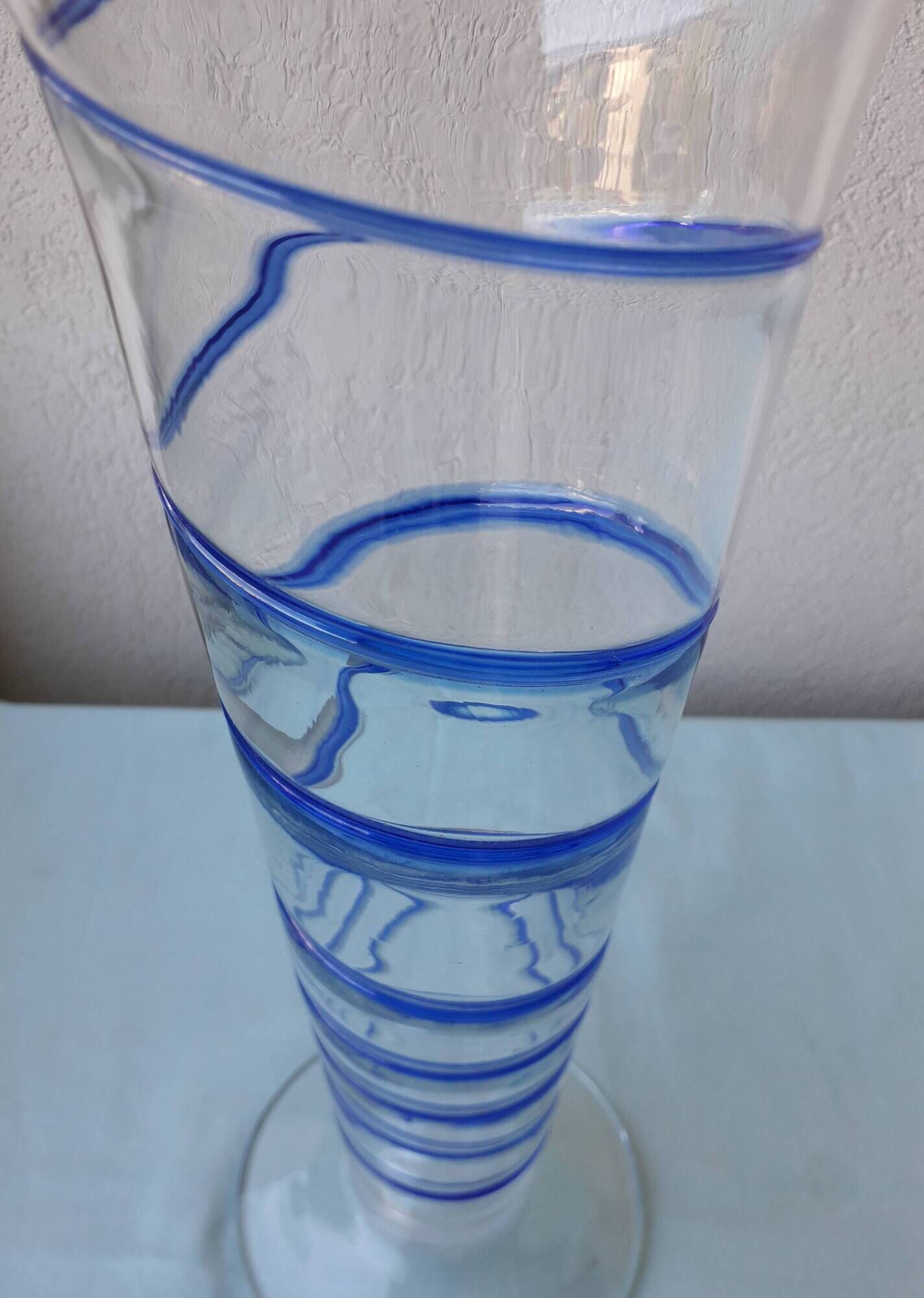Glass vase on a pedestal with a blue trim.