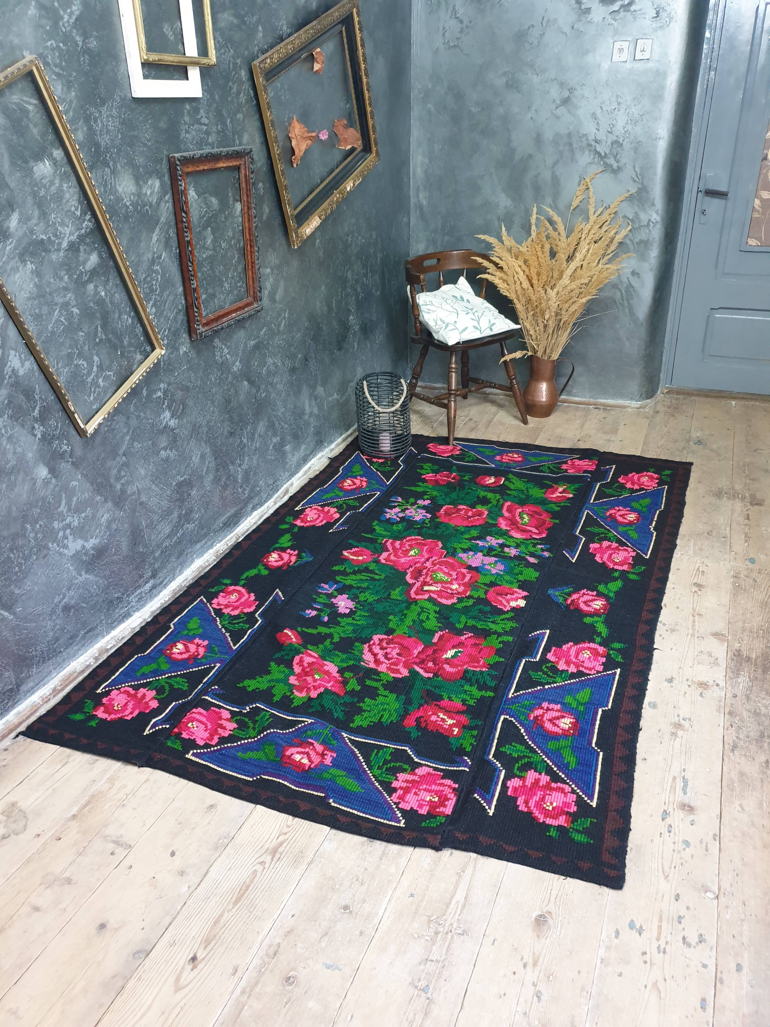 Handwoven floral wool rug, black background with pink roses