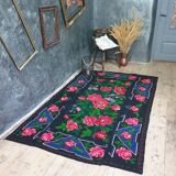 Handwoven floral wool rug, black background with pink roses