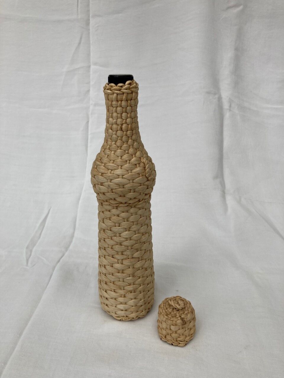 Bottle surrounded by wicker or raffia