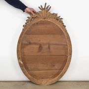 French 19th-century oval mirror in gold leaf with a pediment.