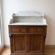 Antique wooden chest of drawers with a marble top.