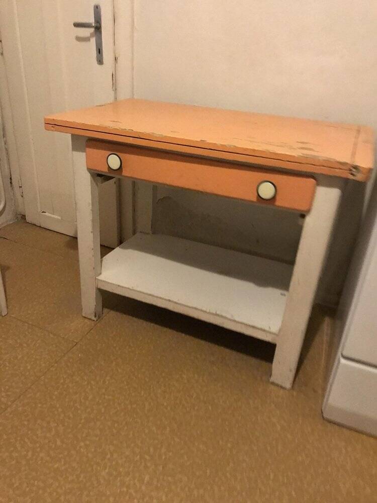 Vintage wooden kitchen table in orange and white with a drawer and low shelf.