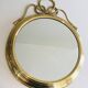 Large decorative oval mirror in brass adorned with a significant twisted bow.