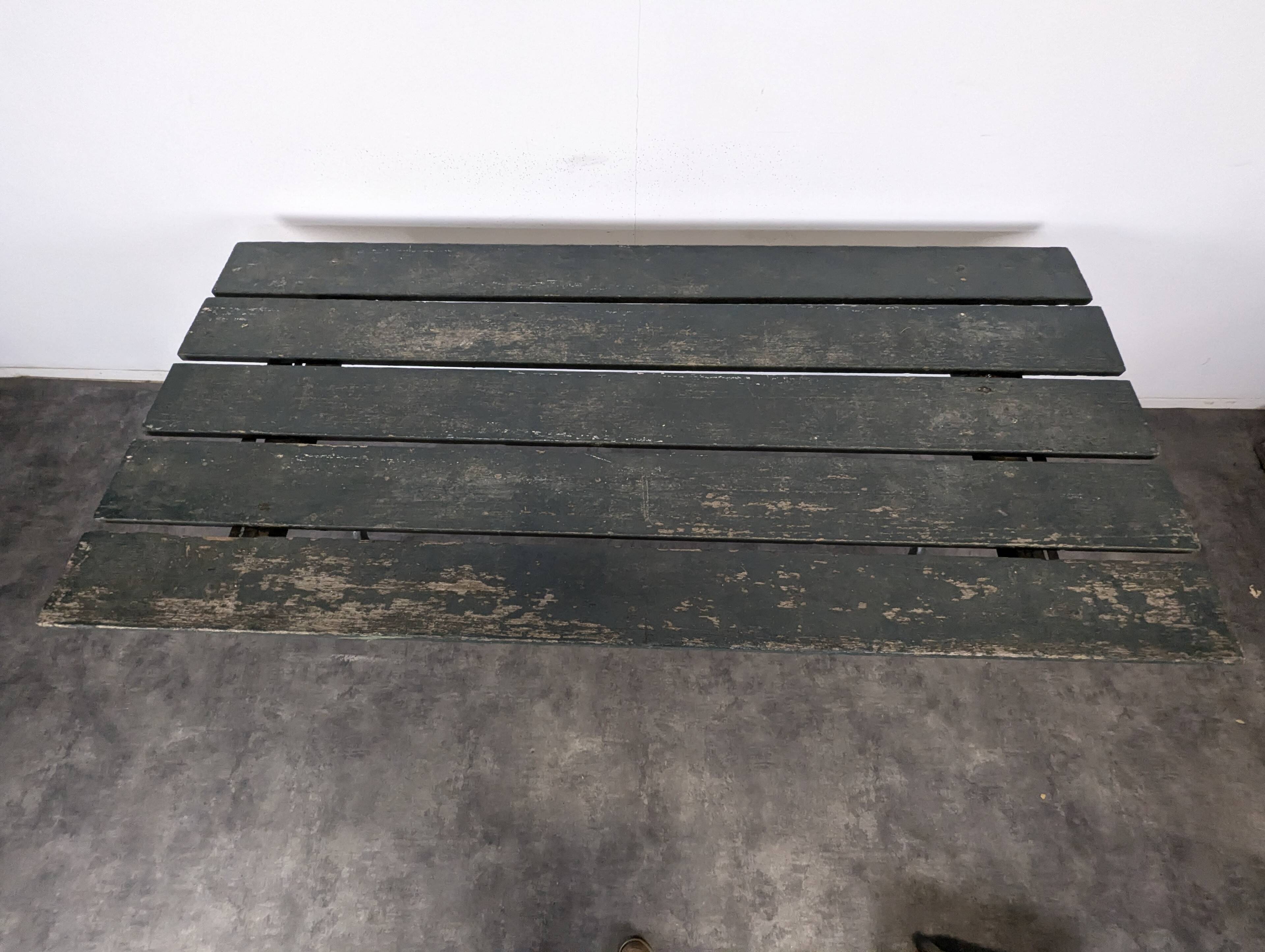 Garden table with a cast iron base and a green painted wooden top.
