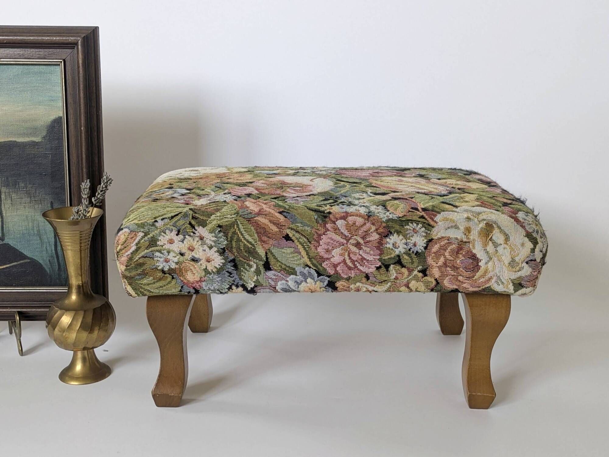 Large vintage upholstered footstool with curved legs.
