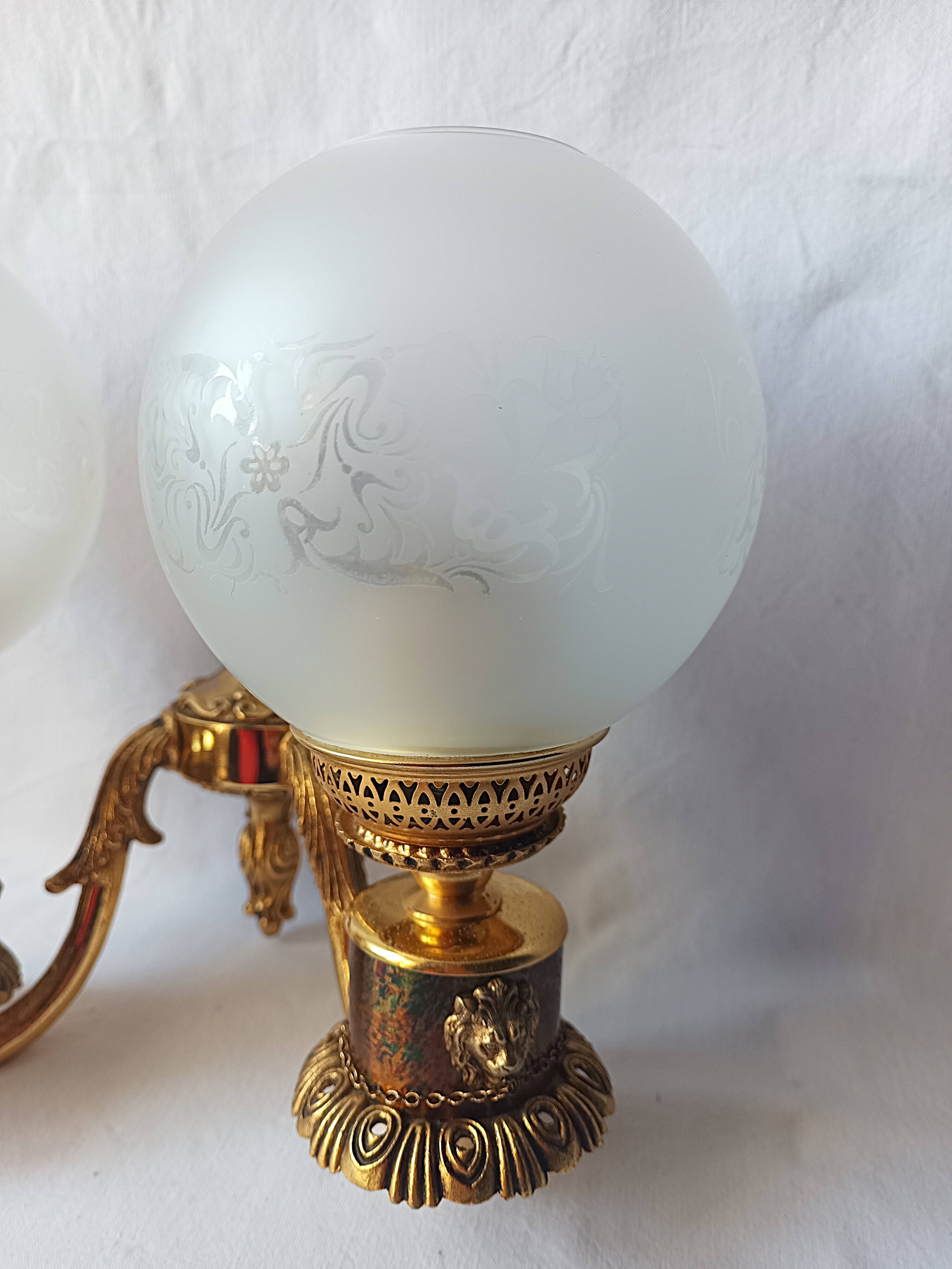 Wall lamp in gilded bronze with a lion's head and engraved globe.