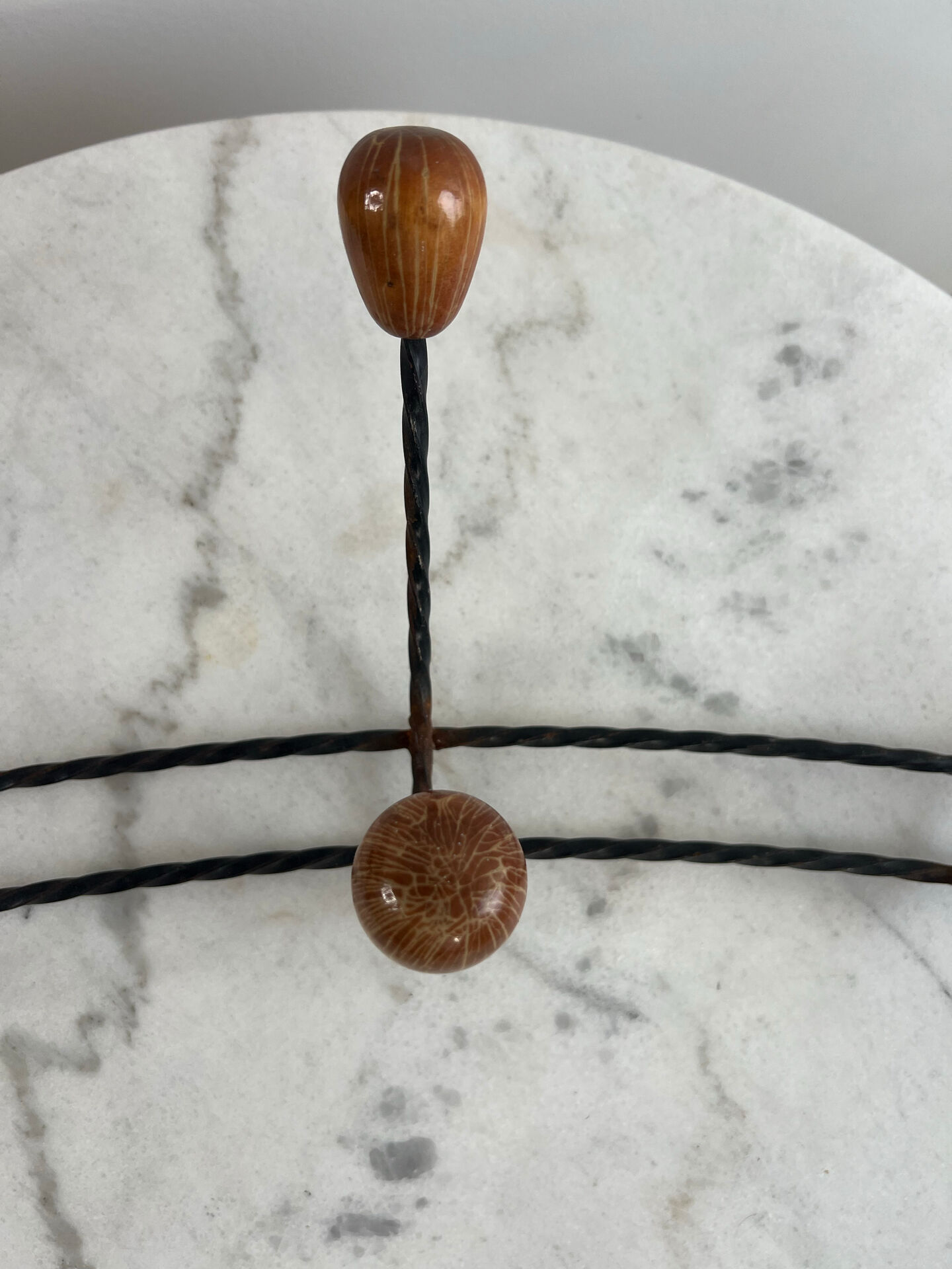 Wall-mounted coat rack in wrought iron with turned wooden knobs.