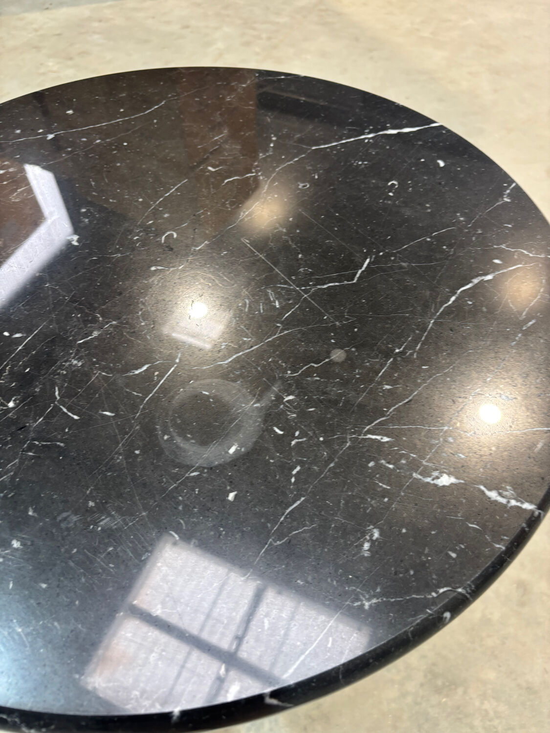 Round marble table with a black metal tulip base.