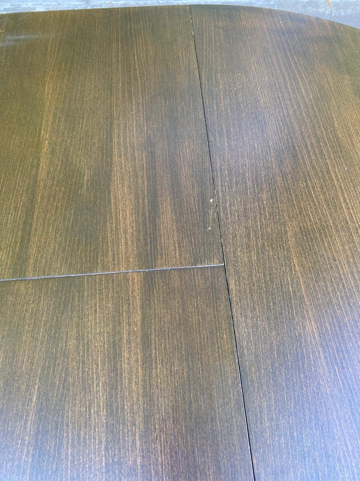 Extendable round table in solid wood with a dark oak satin finish.