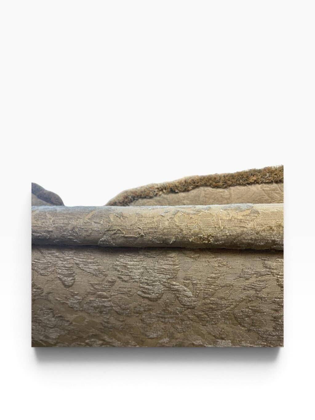 Vintage beige three-seater sofa with floral pattern and fringes.