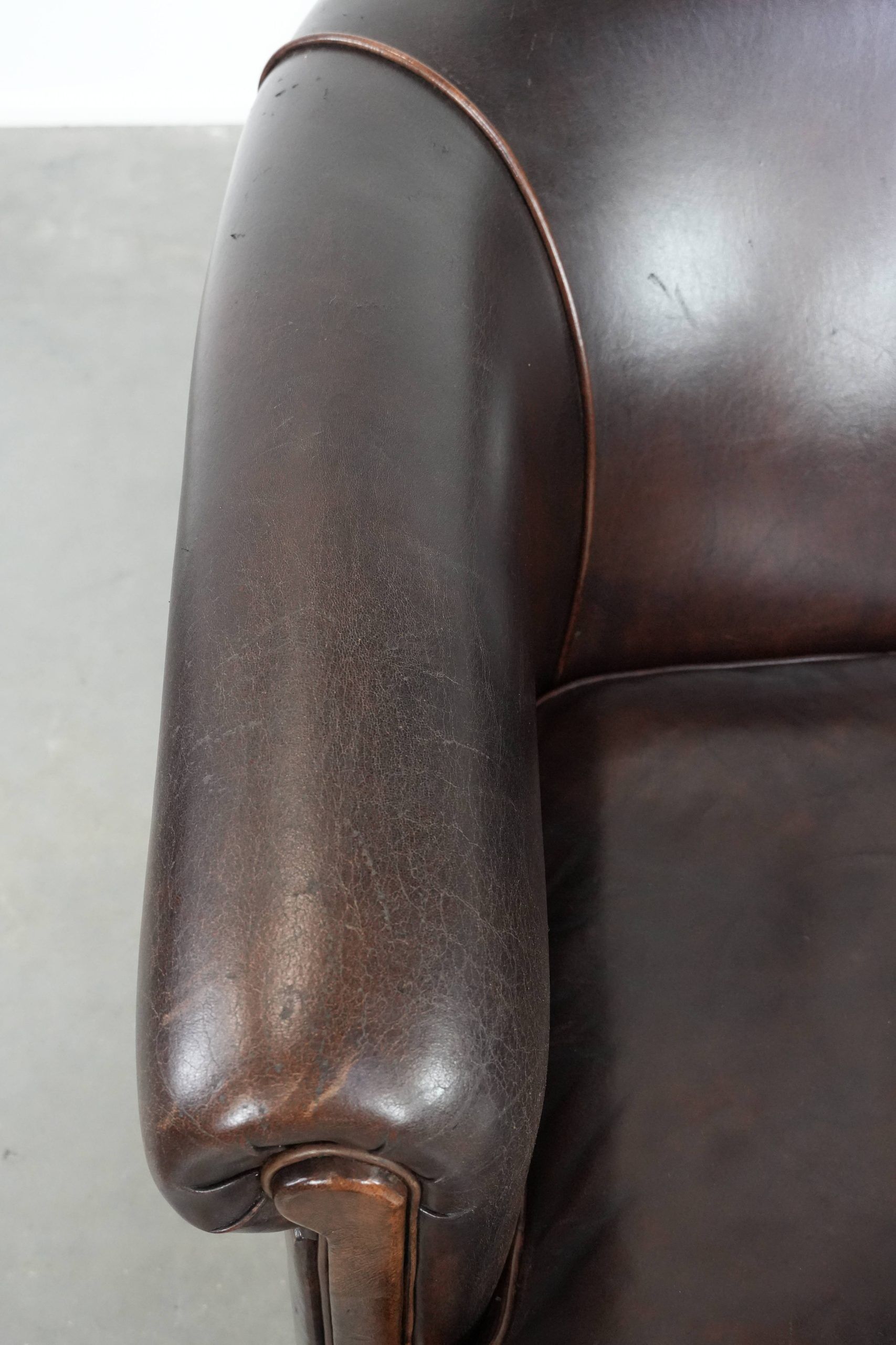 Dark brown vintage club armchair in English style made of sheepskin leather