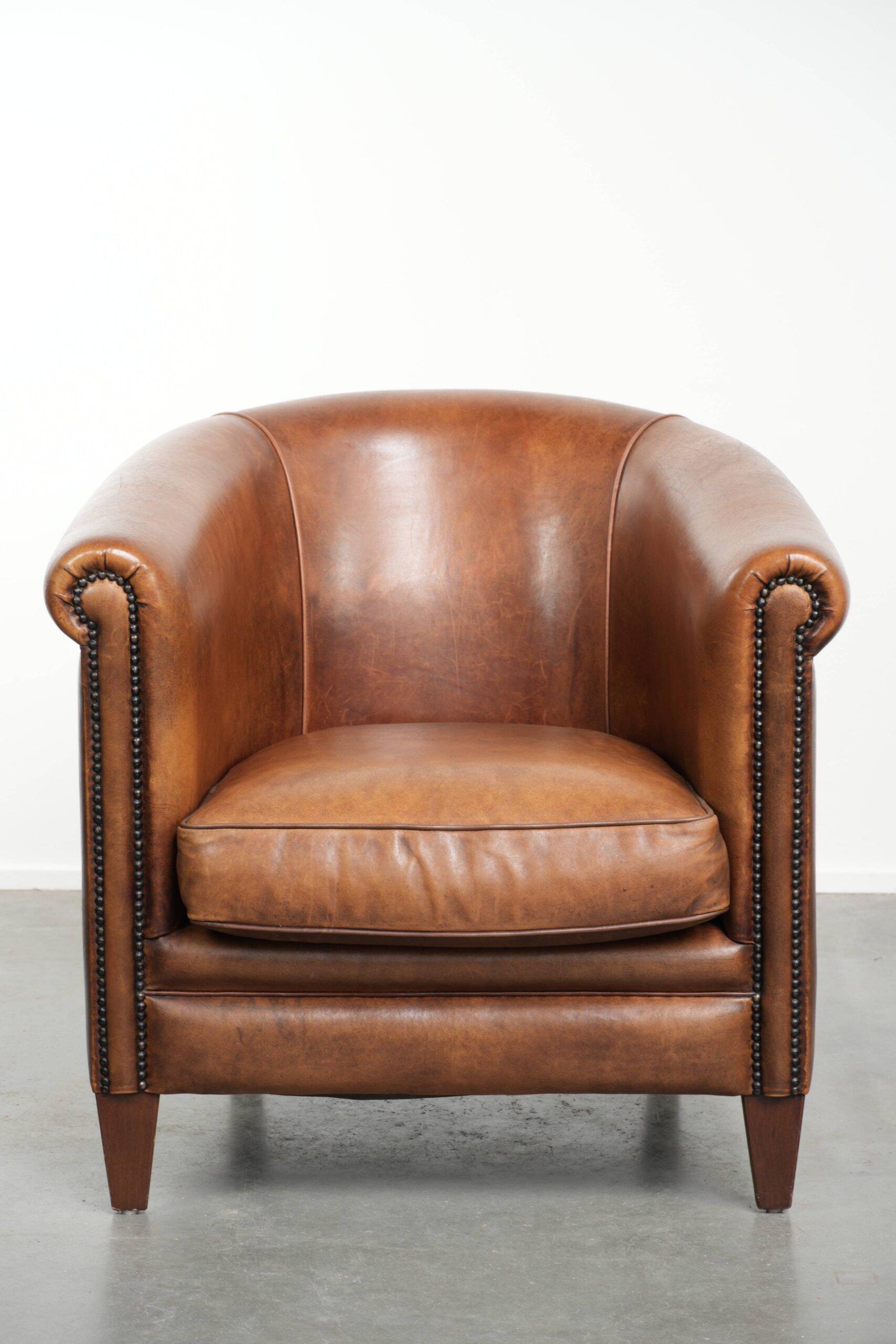 Sheepskin club armchair with a cognac colour finished with decorative nails