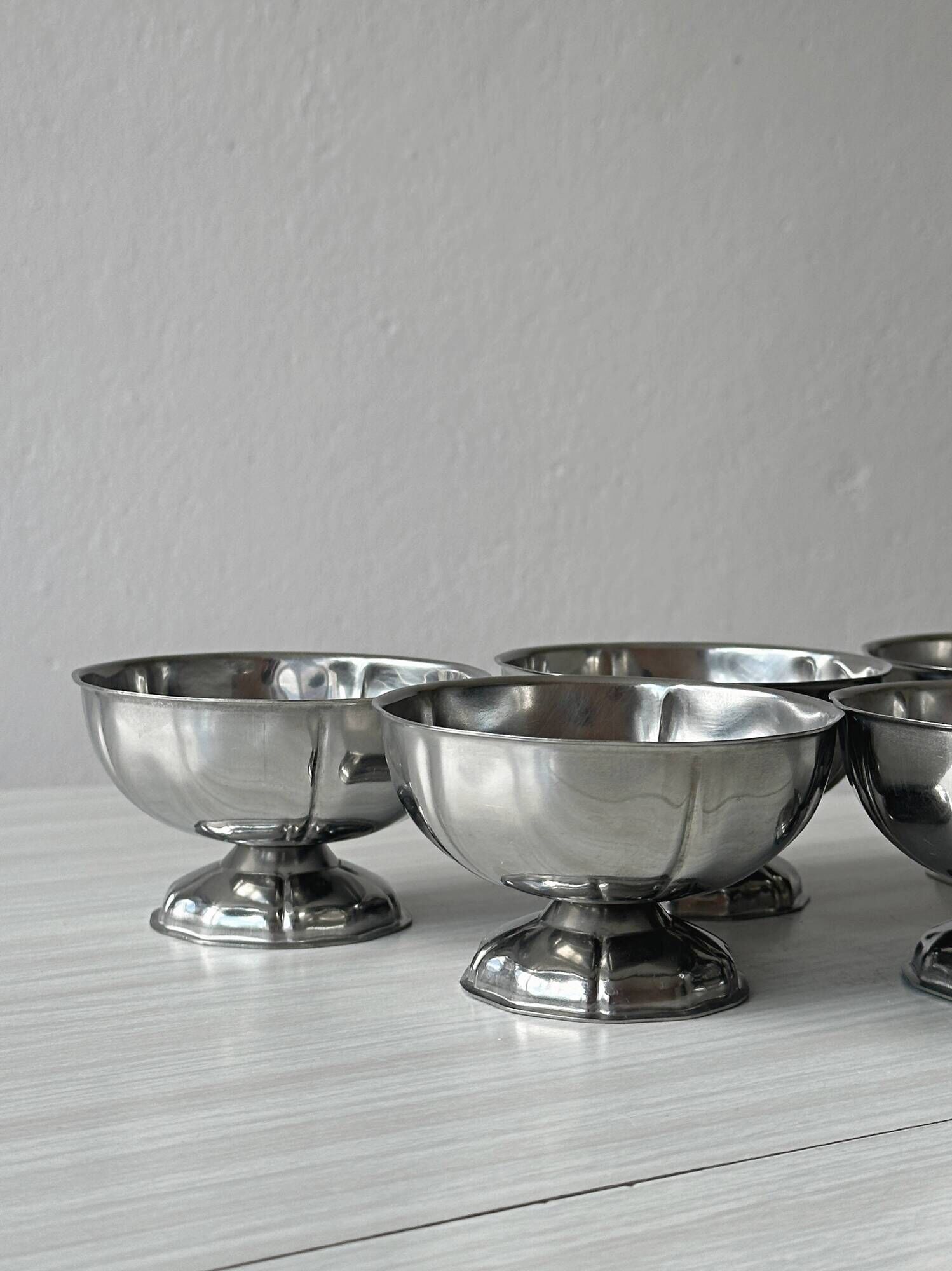 Set of 6 silver stainless steel ice cream bowls on a stand.