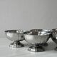 Set of 6 silver stainless steel ice cream bowls on a stand.