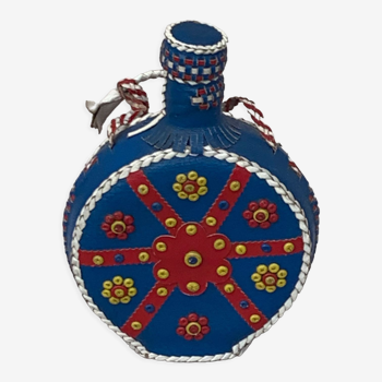 Flacon, bouteille en verre ocre habillée de cuir bleu et rouge