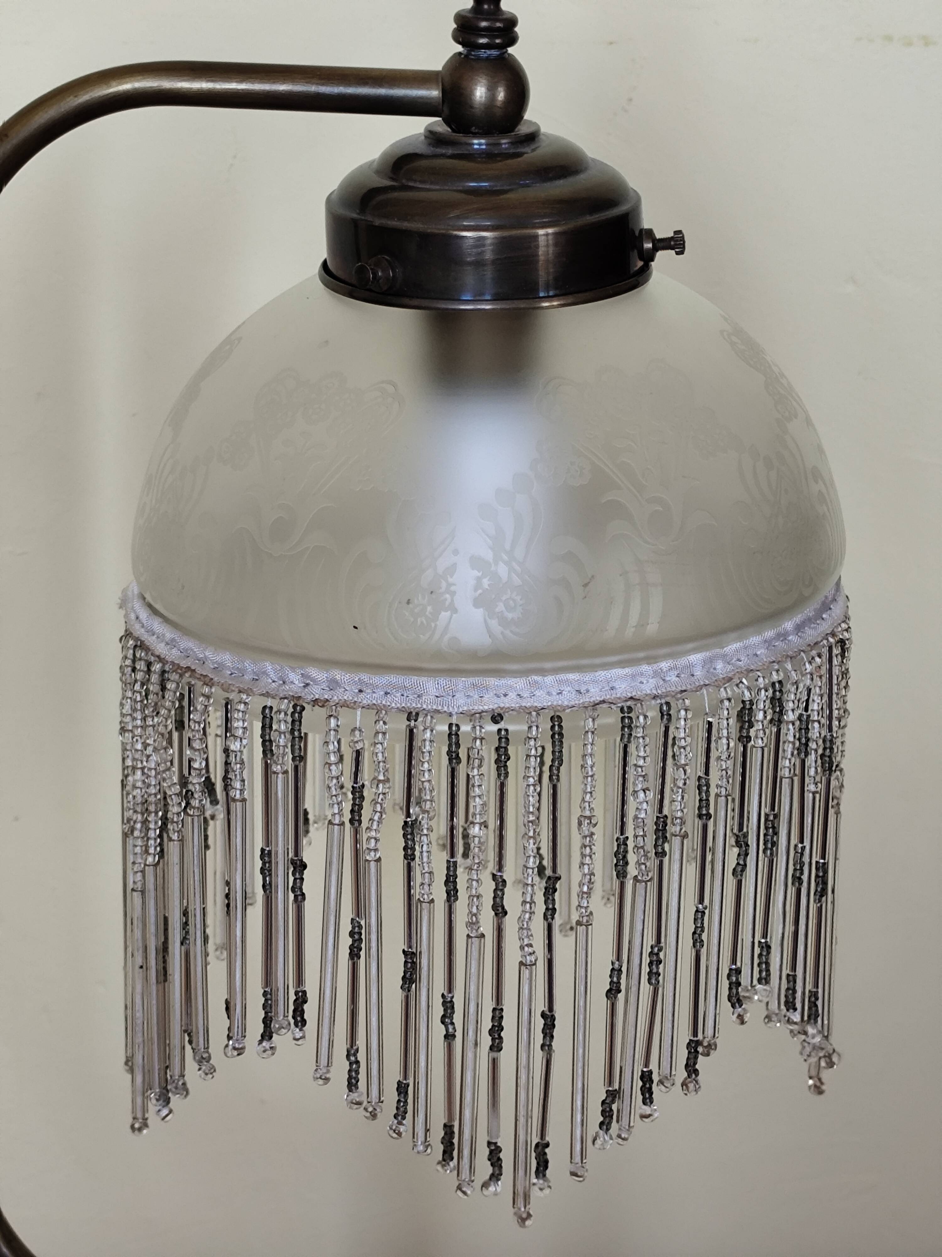 Retro brass lamp with a glass shade and bead fringes.