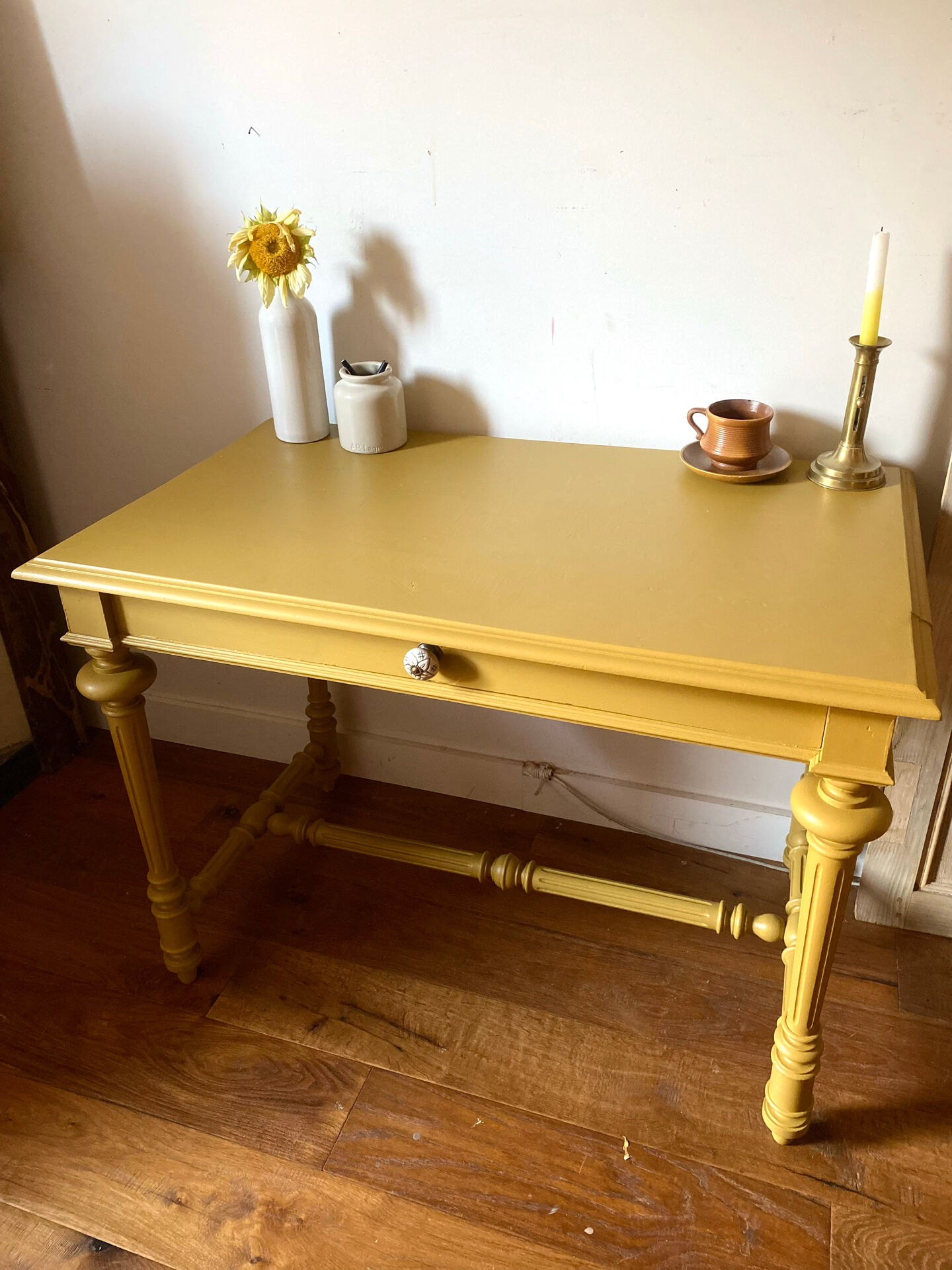 Desk table from the late 19th century, painted mustard, with turned stretcher.