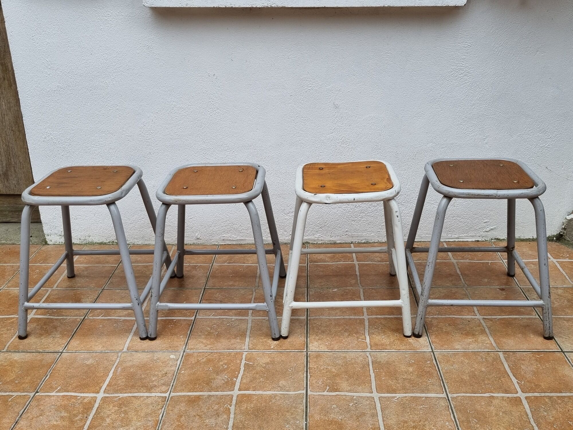 Set of four stackable industrial tubular metal and wood stools