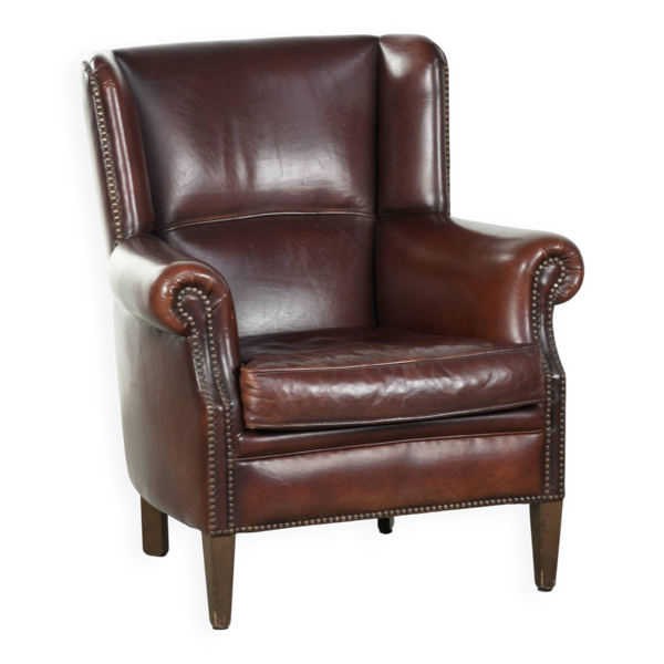 Fauteuil en peau de mouton vintage avec un dossier haut fini avec des clous décoratifs.