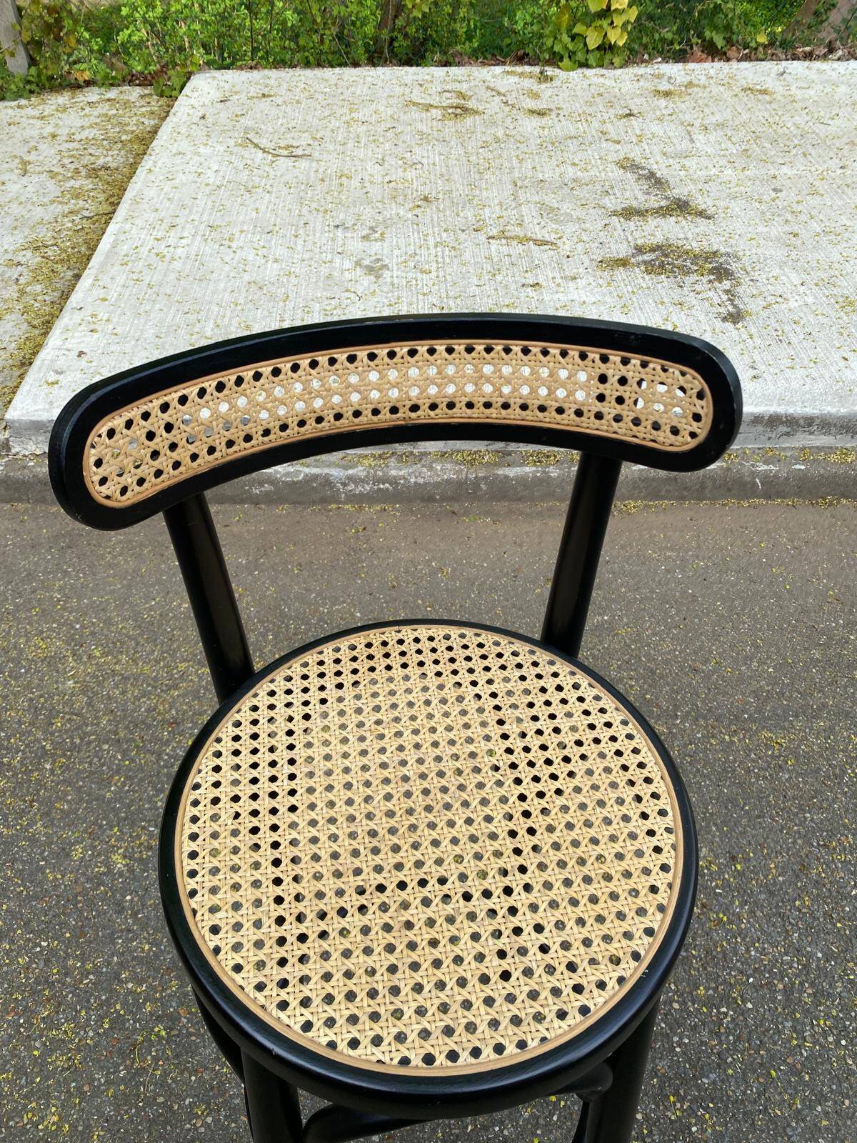 High bistro bar stool in curved black wood with a cane backrest.