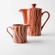 Vintage tea or coffee service in 1970s ceramic, teapot with lid and milk jug, rust orange with retro striped pattern, mid-century decoration, gift idea.