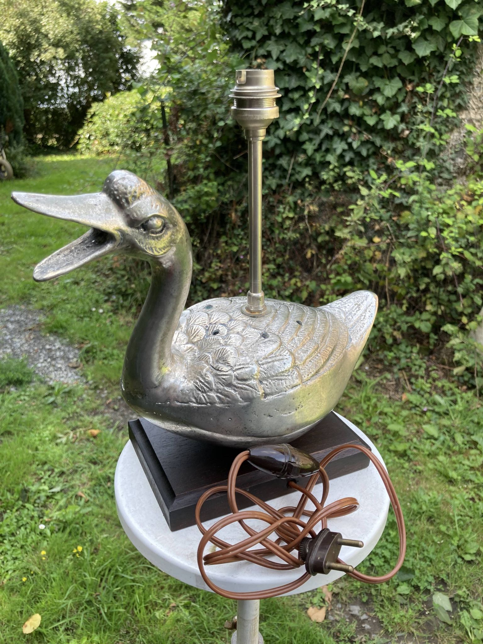 Old vintage lamp representing a duck in silver metal with wooden base