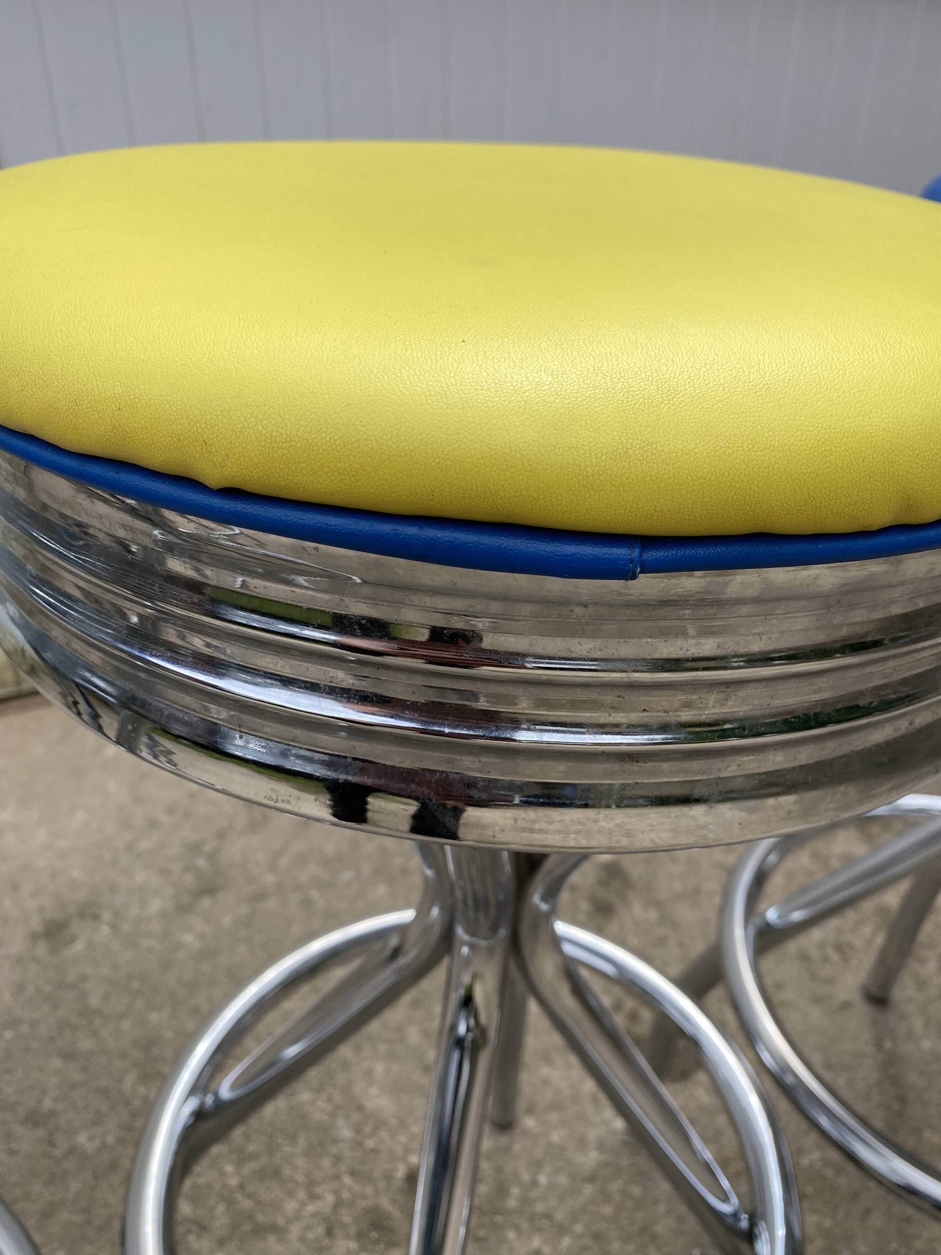 Set of 5 vintage swivel bar stools in blue, red, orange, and yellow.
