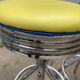 Set of 5 vintage swivel bar stools in blue, red, orange, and yellow.