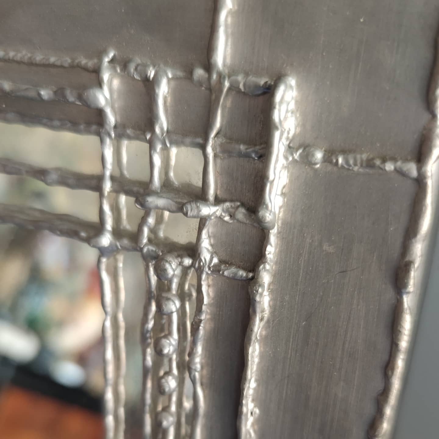 Pewter mirror on a brutalist-style wooden stand