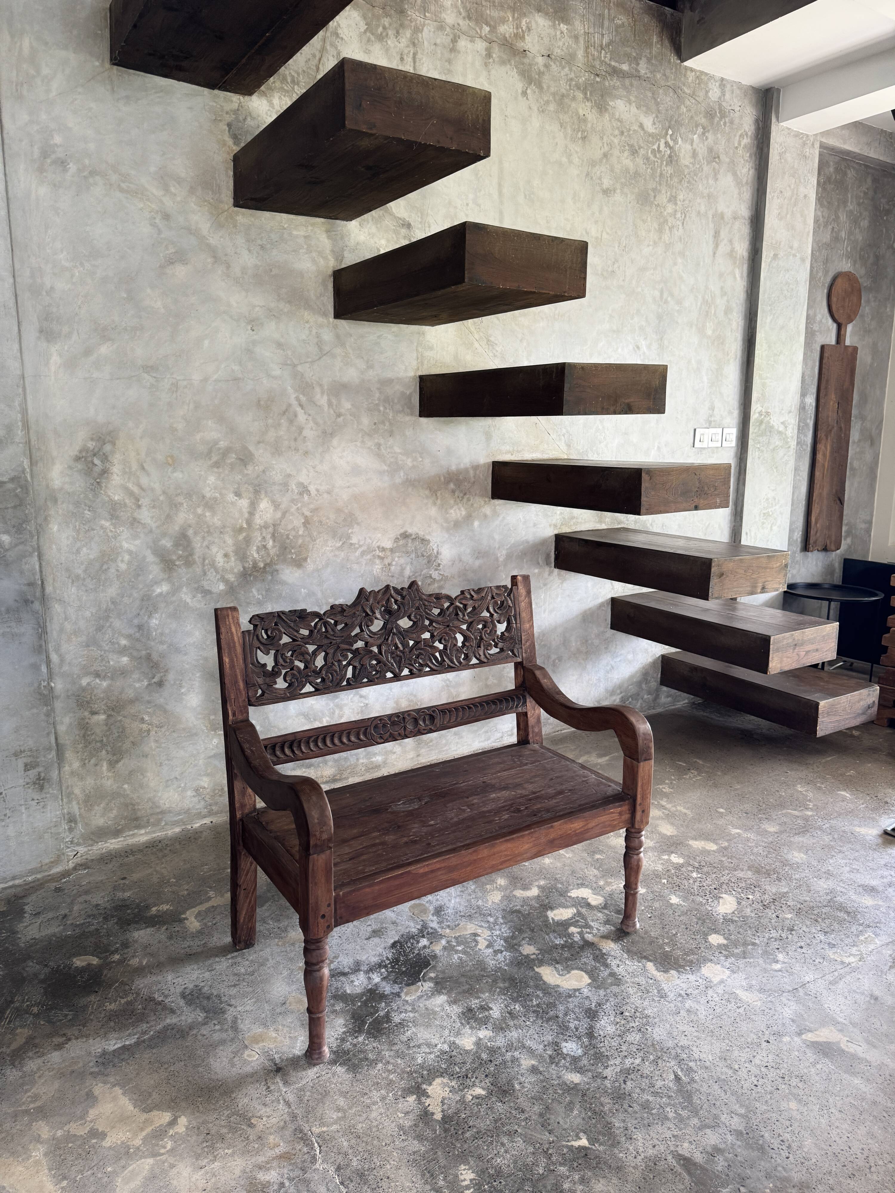 Small antique Indonesian bench in carved teak with plant and floral motifs.