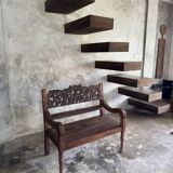 Small antique Indonesian bench in carved teak with plant and floral motifs.