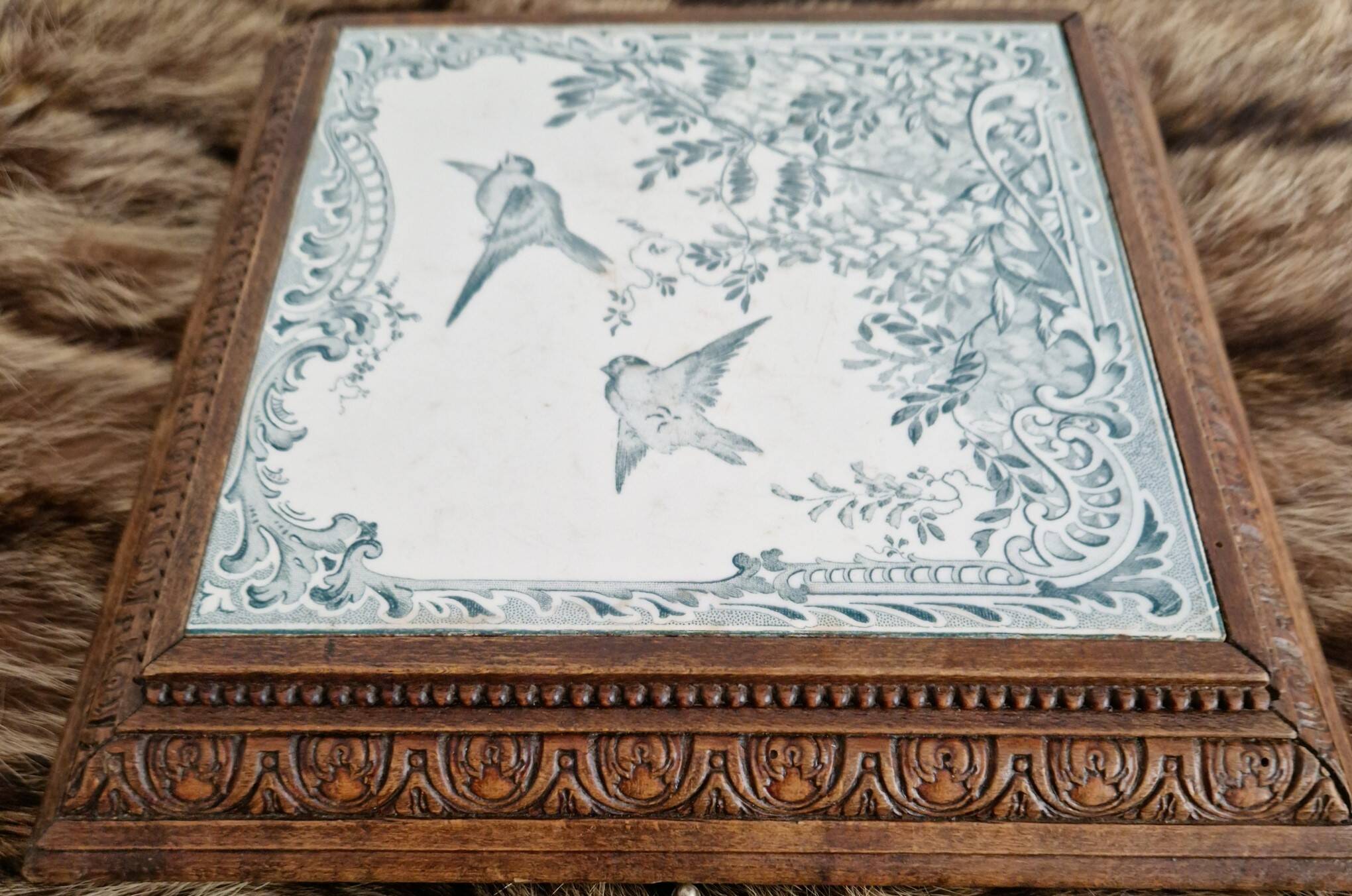Antique musical trivet made of carved wood and Belle Époque earthenware.