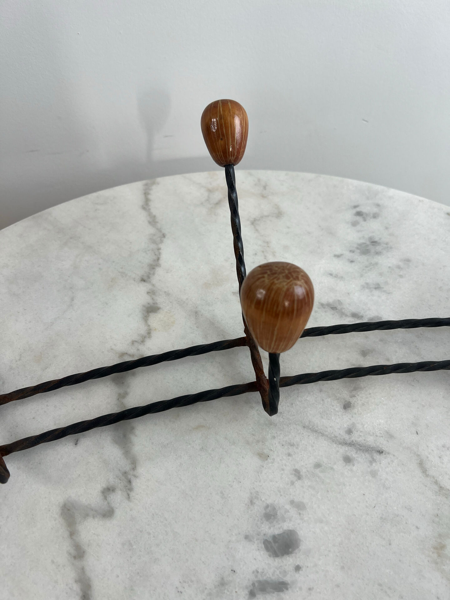 Wall-mounted coat rack in wrought iron with turned wooden knobs.