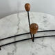 Wall-mounted coat rack in wrought iron with turned wooden knobs.