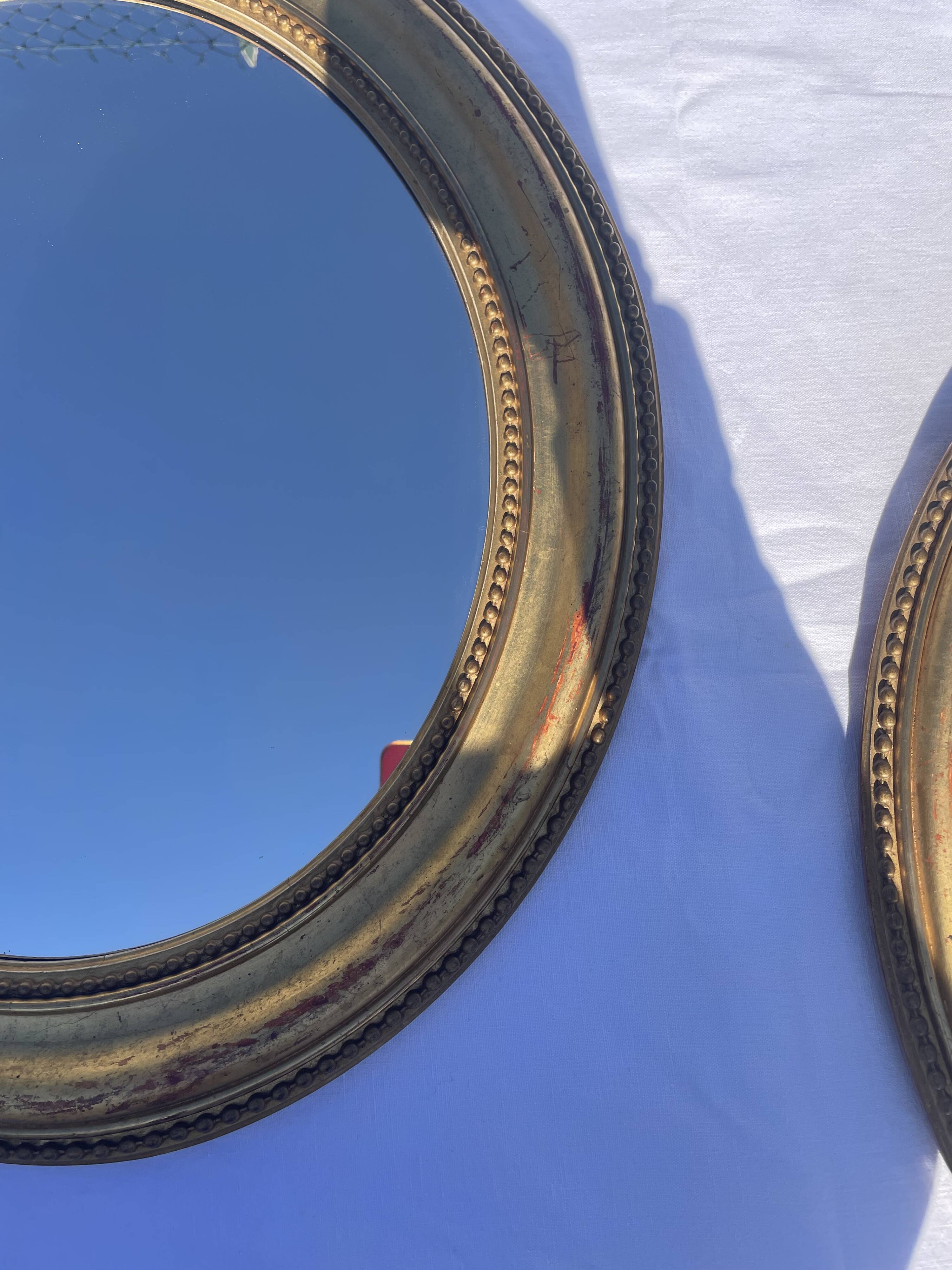 Duo de miroirs ovales et dorés en bois